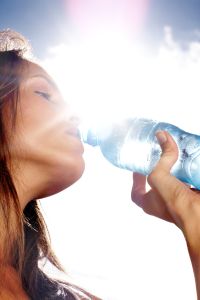 Thirsty woman drinking water on a sunny day