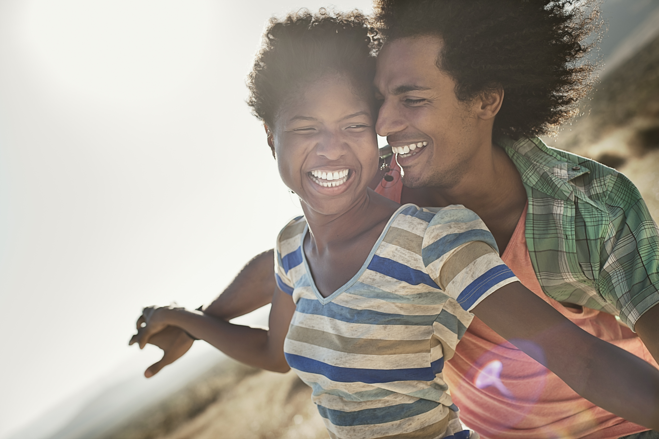A couple with arms outstretched in a gesture of freedom and excitement, leaning into the breeze.