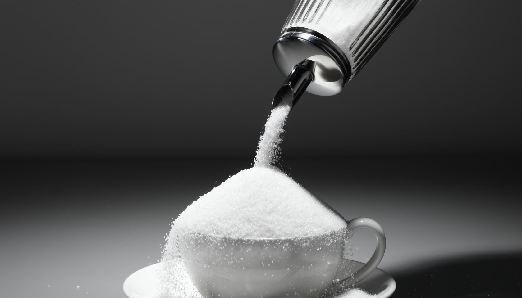 Sugar being poured into tea cup, close-up