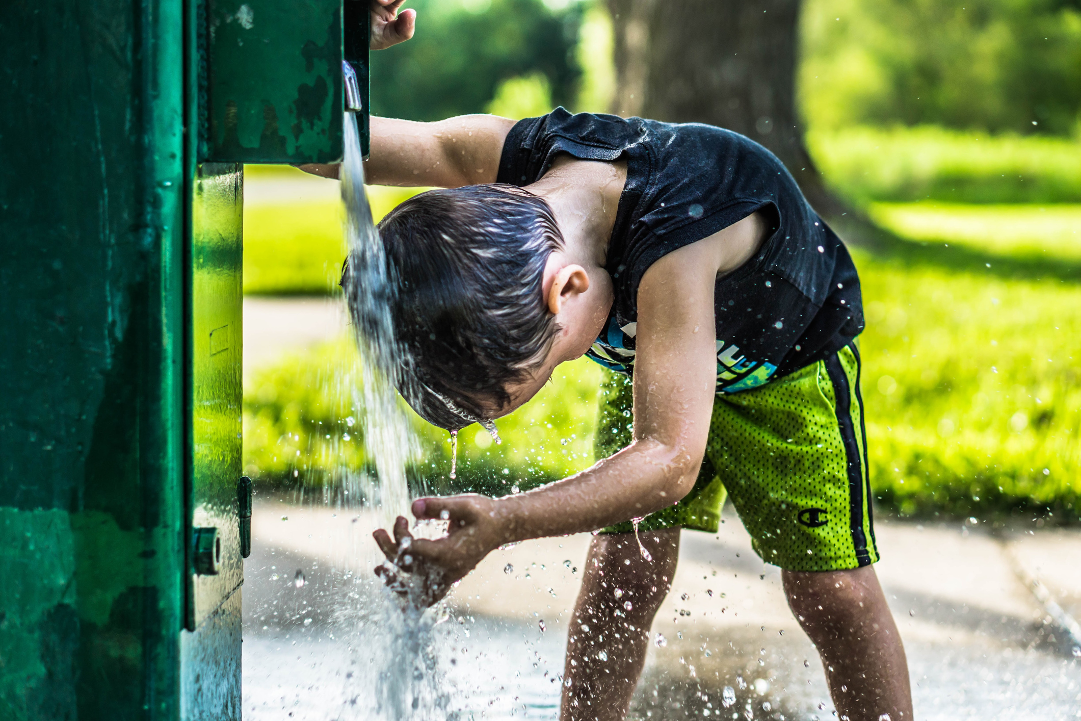 A Boy Washing Head At Drinking Fountain