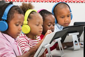 Students using digital tablets with headphones in classroom