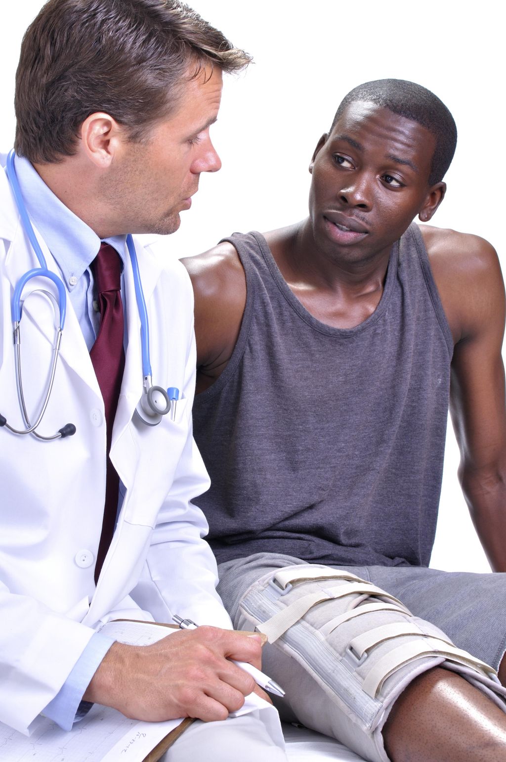 Medical doctor meets with young black male patient with leg brace in clinic with white background