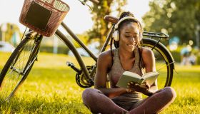 Young African American woman is reading a book in nature