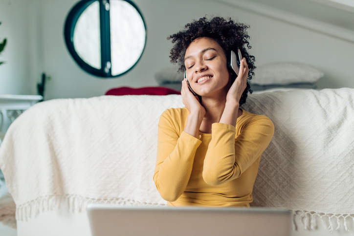 Portrait of a beautiful Afro woman enjoying music at her bedroom