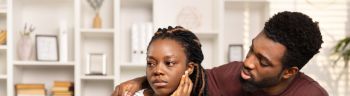 Concerned Man Comforting Upset Woman On Couch At Home