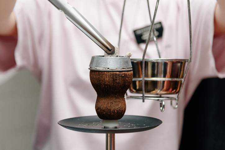 hookah woman changes coals in hookah bowl with tongs, no face, unrecognizable