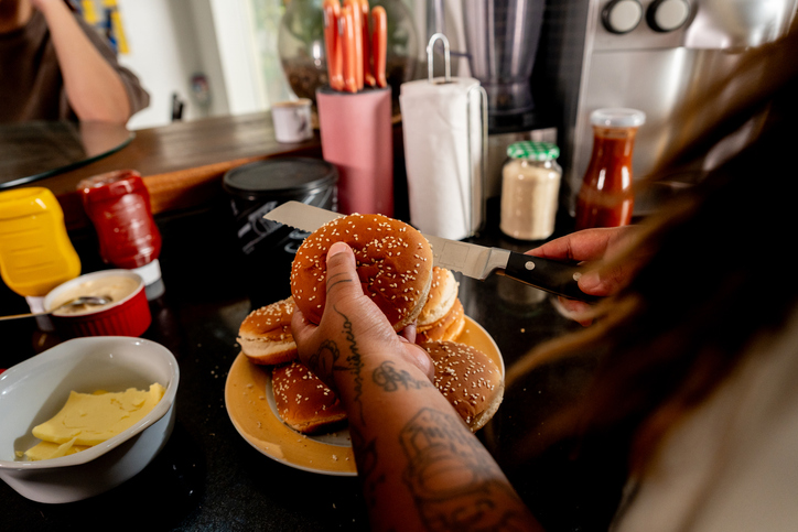 Close-up of woman cutting bread for hamburguer