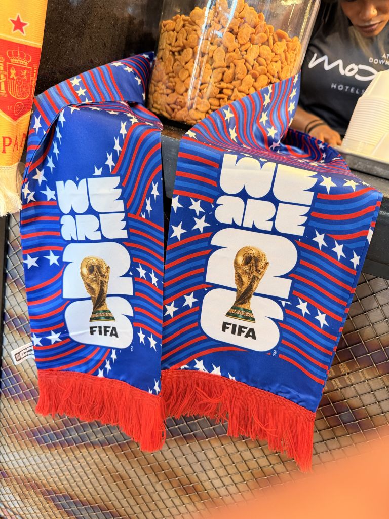 Colorful FIFA World Cup-themed merchandise, including scarves and a jar of snacks, displayed on a tiled surface.