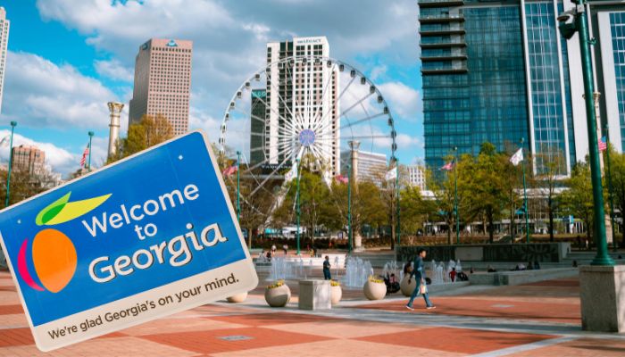 Welcome to Georgia sign in front of a city skyline with a Ferris wheel and people walking around.