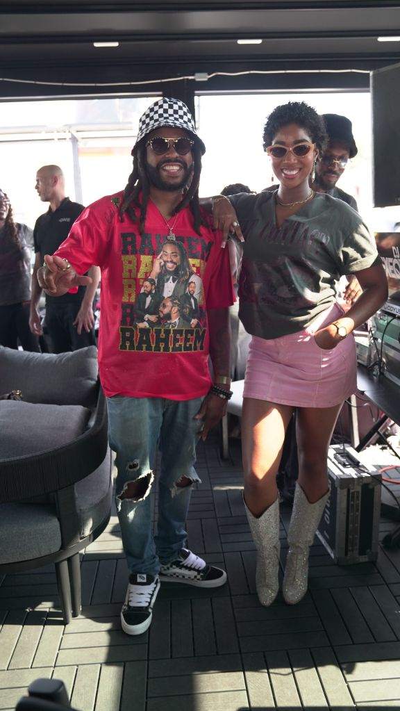 Two people smiling and posing together, one wearing a red "Randy Rhoads" t-shirt and a checkered hat, the other wearing a pink skirt and glittery boots.