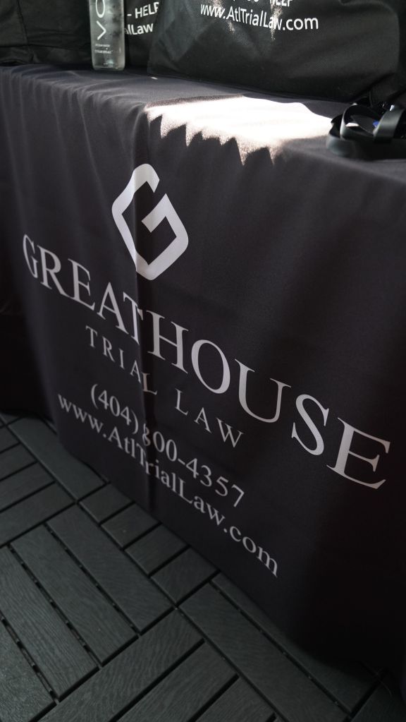 A black bag with the text "GREATHOUSE TRIAL LAW" and contact information.