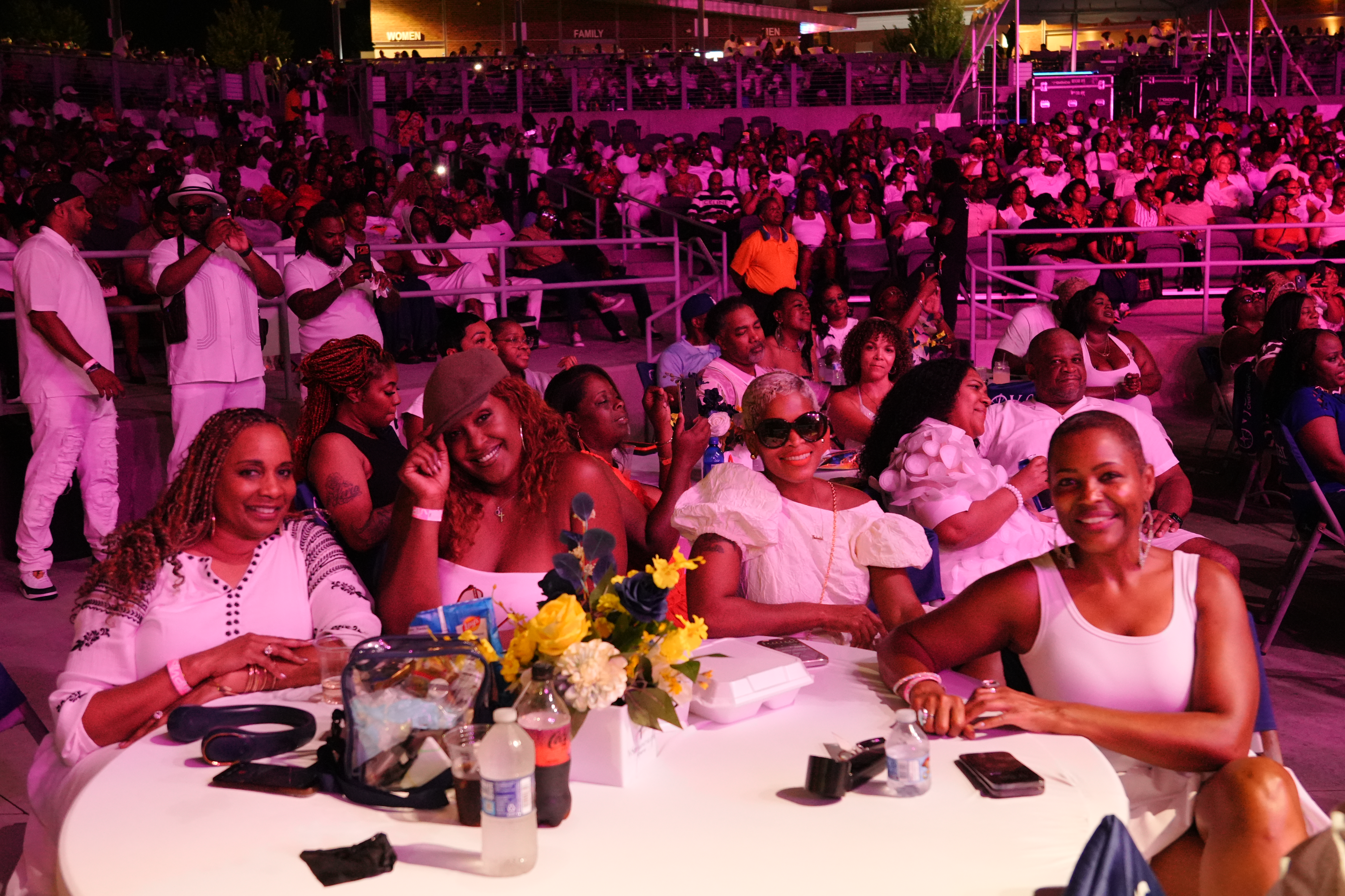 A crowded nighttime outdoor event with a large group of people dressed in colorful, festive attire enjoying the atmosphere and entertainment.