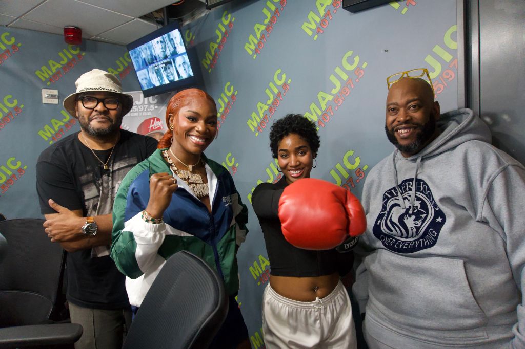 Four people posing in a room with "MAJIC" branding on the walls, one person wearing boxing gloves.